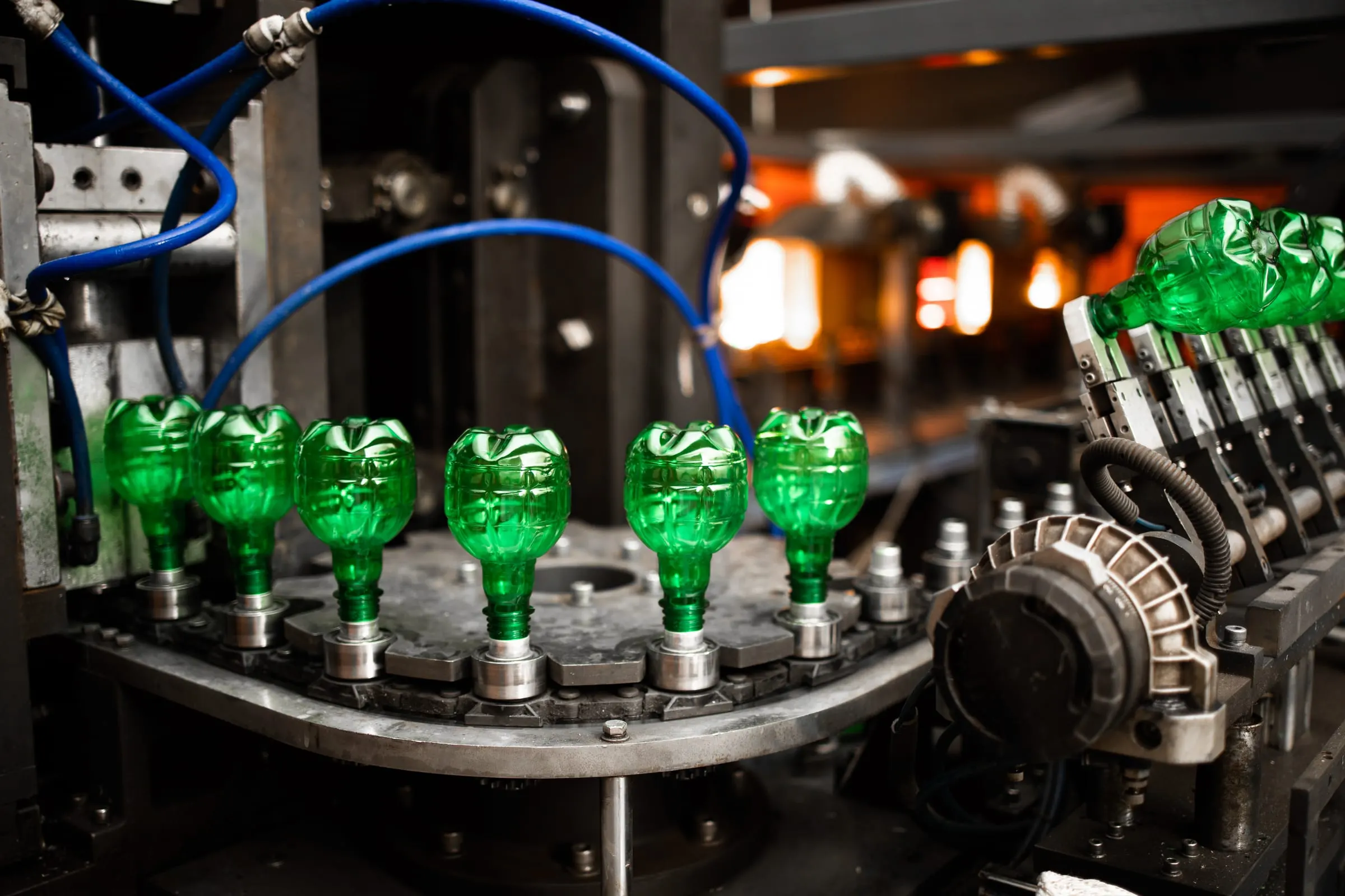 Green PET bottles moving through a blow-moulding machine on the Nutricom line.
