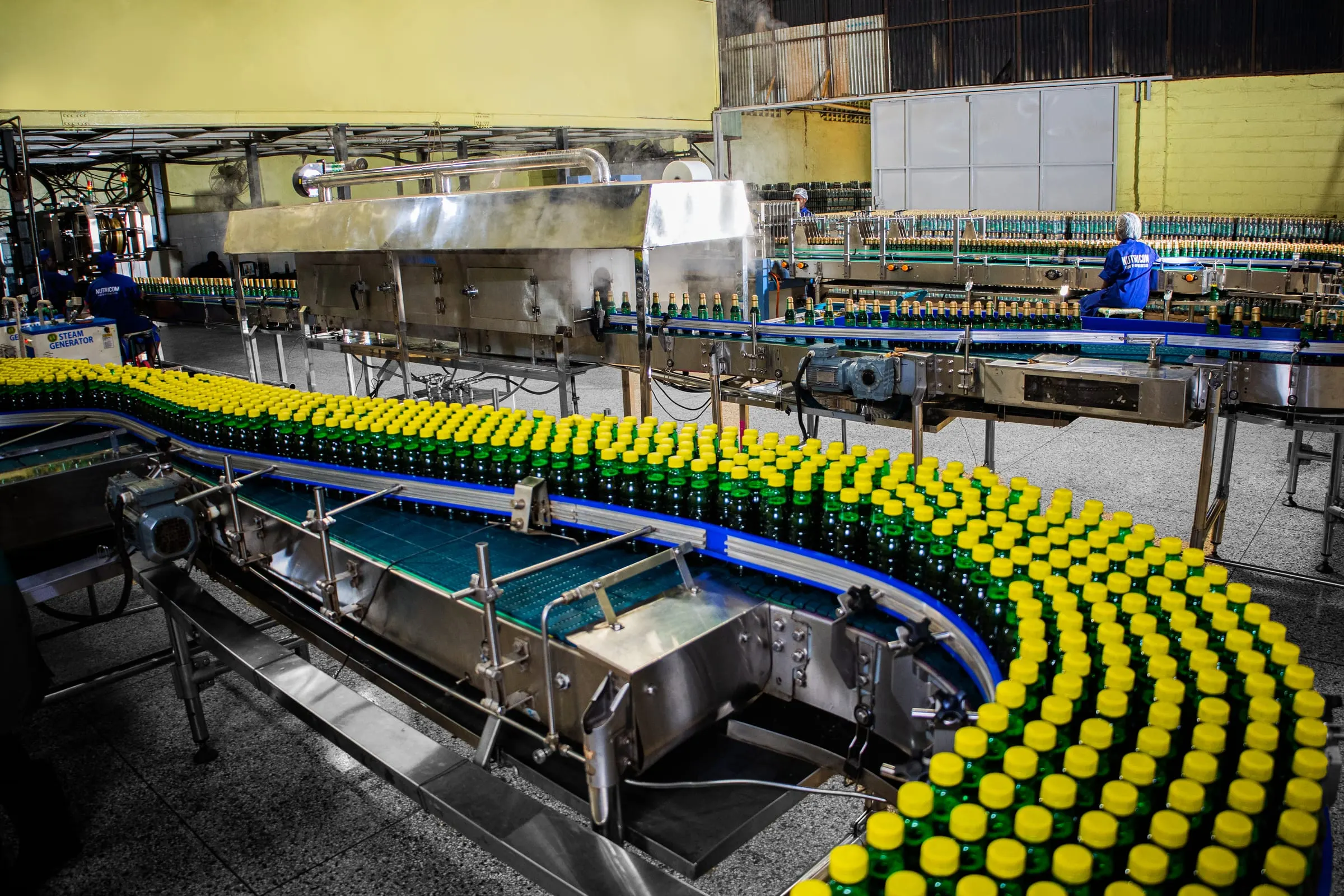 A long conveyor curve carrying capped bottles through the plant.