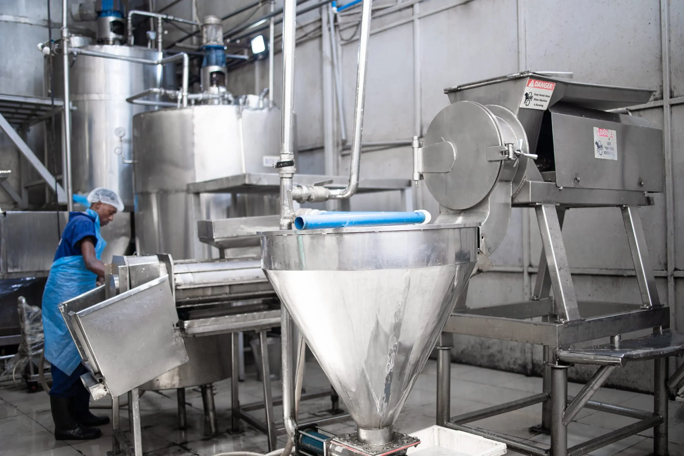 A plant worker loading a processing hopper.